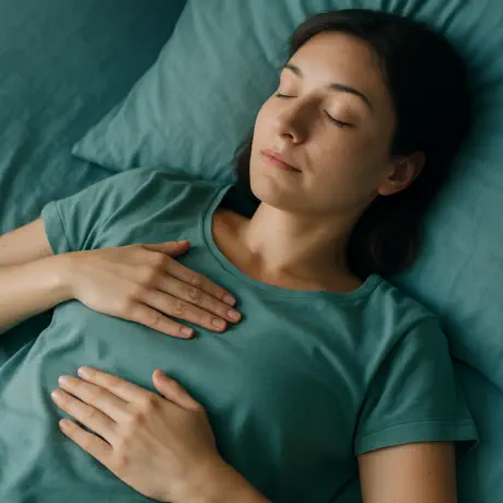 Person lying calmly with hands on chest and abdomen, practising gentle belly breathing for relaxation and emotional balance