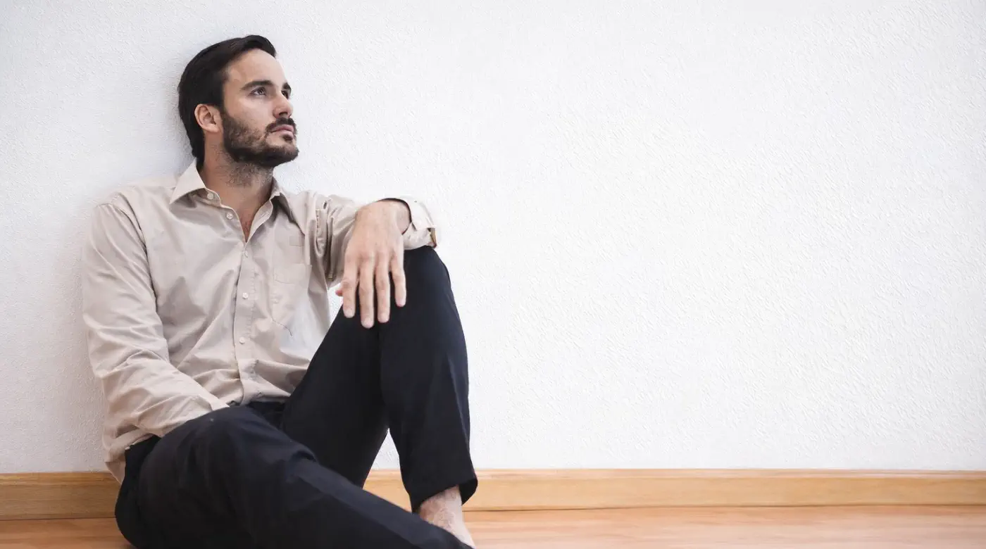 Ignoring Emotions Has Consequences Man sitting alone against a wall, reflecting quietly while experiencing emotional tension