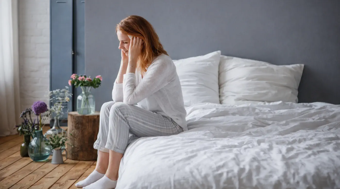 You Cannot Avoid Your Pain — Unacknowledged Emotions Woman sitting on a bed in quiet distress, reflecting on unacknowledged emotional pain